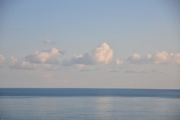 Few light clouds above the horizon and Mediterranean sea with reflections in the evening.