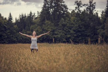 Woman standing in the middle of meadow with her arms spread open