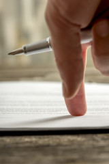 Male hand pointing to a line at the end of a document
