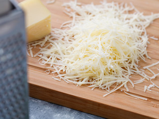 Grated parmesan cheese on a wooden board. Cooking food.