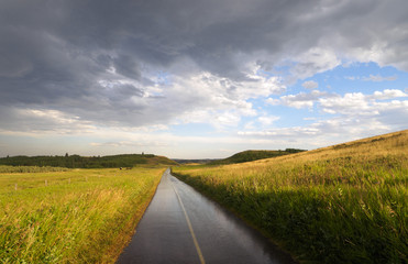 Rainy Bike path through the countryside prairie fields and rolling hills with rain clouds