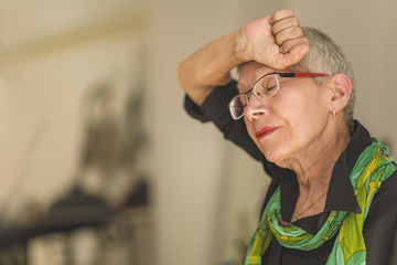 Elderly woman suffering from headache at home