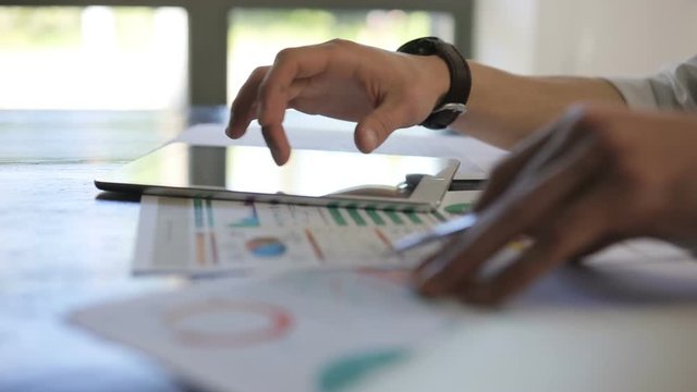 Closeup of young businessman hands, using laptop phablet pad and performing analytics work research in office slow motion