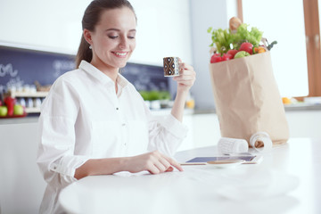 Young woman planning expenses and paying bills on her kitchen.