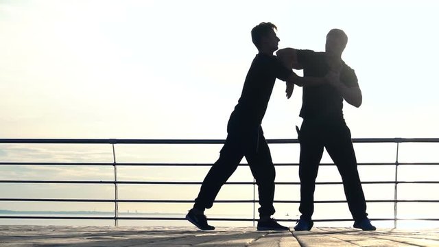 Young man fight training against sunrise in slow motion