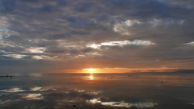 A colorful sunrise video from Dumaguete City shores, with mirror like ocean. Silhouettes of locals can be seen gathering shells from the sandbar. Presented in real time.