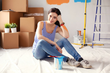 Happy smiling woman painting interior wall of new house. Happy smiling woman