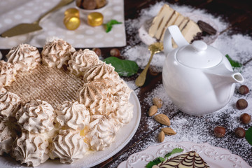 Beautifully decorated dessert table where the cake with meringue on a dark wooden table. Arrangement of delicious sweets