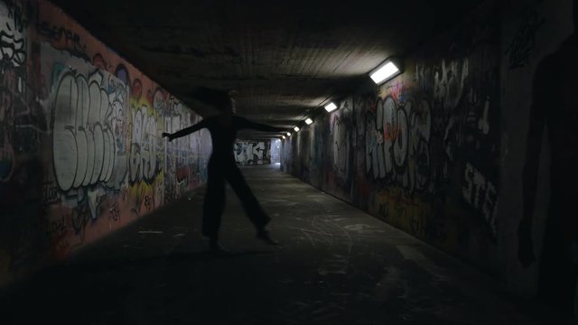 Young Woman Dancing in Dark Spray Painted Underpass