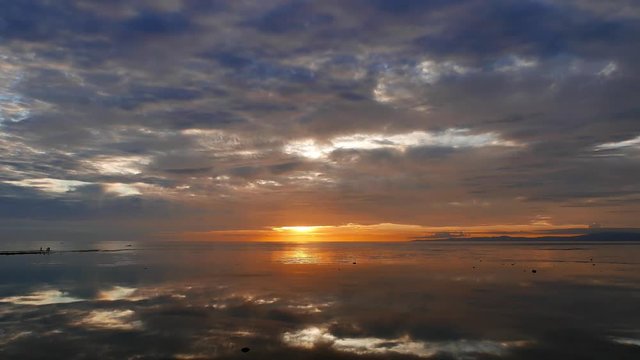 A colorful, overcast sunrise video from Dumaguete City shores, with mirror like ocean reflecting the sky. Presented in real time.