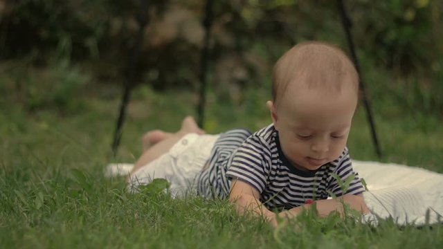 A small child lies on the grass grins and plays close-up