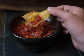 Hand holding chip full of homemade salsa