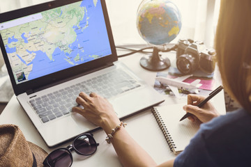 Young women planning vacation trip and searching information or booking an hotel on laptop