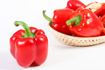 Red ripe peppers with wicker basket on white background, healthy nutrition