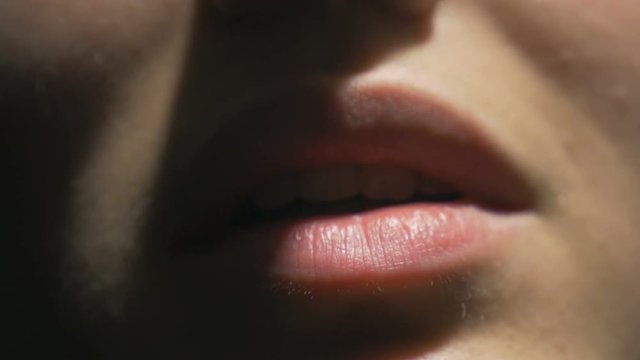 A young female's lips under a spotlight as she speaks. An extreme close up shot.