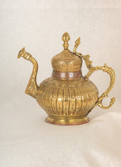 a copper jug with Arabic ornament and engraving on a light fabric. antique dishes