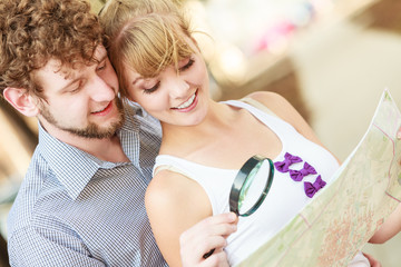 Tourist couple in city looking up directions on map