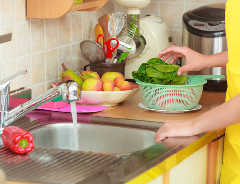 woman washing fresh vegetables in kitchen