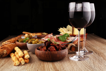 Italian antipasti wine snacks set. Cheese variety, Mediterranean olives, pickles, Prosciutto di Parma, tomatoes, artichokes and wine in glasses