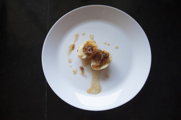 Egg with Tamarind Sauce Split On a white tile plate Placed on black tile floor.
