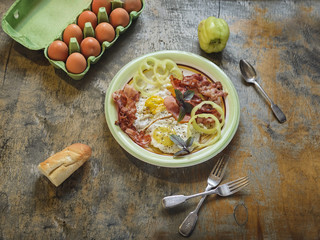 A hearty breakfast of scrambled eggs with bacon and green basil