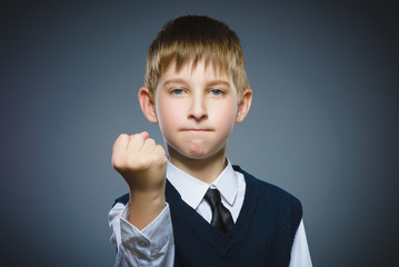 angry boy isolated on gray background. He raised his fists to strike. Closeup