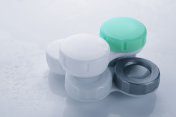 Containers with contact lenses on white background