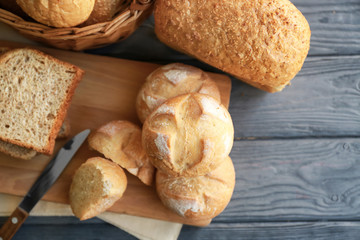 Delicious bread on cutting board on wooden background
