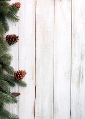 Christmas background - fir leaves and pine cones decorating rustic elements on white wood table....