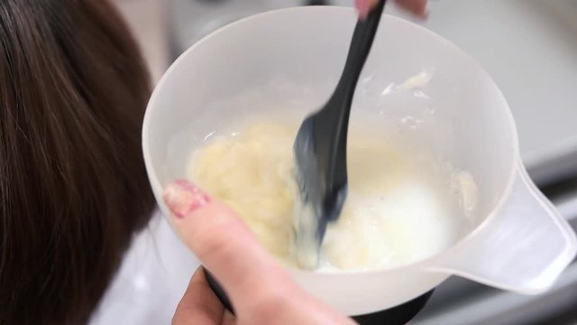 Female hands mixing hair dye. Bowl with hair dye, brush. Hair dye recommendations.