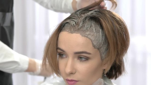 Hair dying process, beauty salon. Face of attractive young woman.