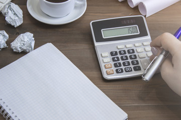 Top view of, calculation in empty notepad placed on office desktop keyboard, coffee cup