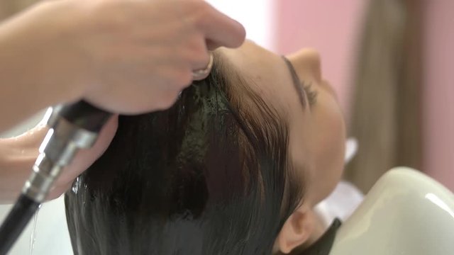 Hands of beautician rinsing hair. Person getting head washed.