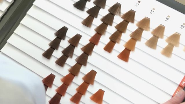 Female hand, hair color chart. Samples of dyed hair.
