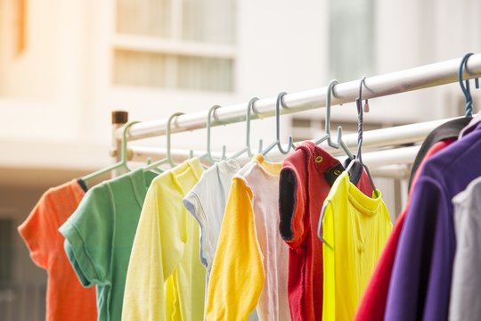 This picture depicts a colorful baby shirt hanging on an outdoor clothes rack. Washing concept