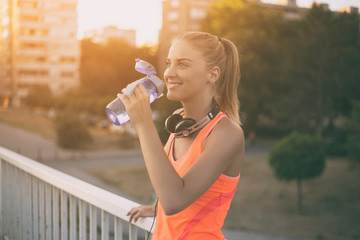 Beautiful sporty woman drinking water while resting from exercise.