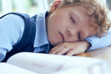 Tired schoolboy sleeping in classroom at school