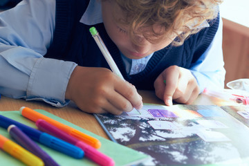 Little child writing with colorful pencils at school. Elementary school and education concept.