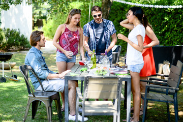 group of friends having fun picnic lunch party outdoor in backyard during summer holiday vacation