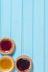 Three colourful jam tarts on a blue background with copy space 