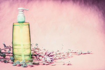 Natural cosmetic product bottle with green lotion or tonic liquid with fresh herbs and flowers at...