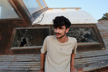 Young man next to an old boat with broken glass