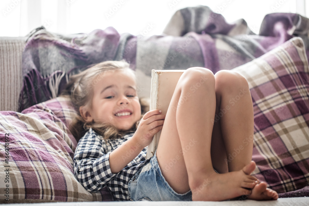 Poster little girl reading book on sofa