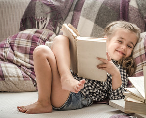 little girl reading book on sofa