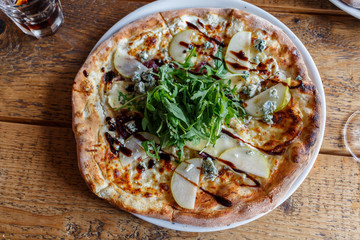 Four cheese pizza on a white plate with rucola lettuce