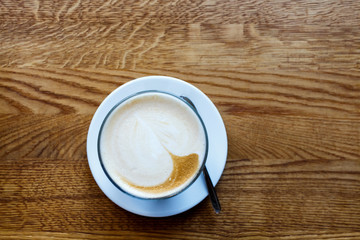 Coffee latte on a wooden table in a small mug
