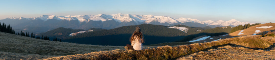 Panoramic rearview shot of a female enjoying gorgeous view in the early morning sitting on top of a mountain resting after hiking copyspace people sport activity lifestyle travelling tourism