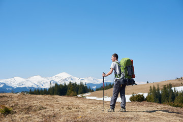 Rearview of an adventurous man with hiking equipment using trekking sticks while walking the mountain copyspace travelling adventure nature landscape sport activity