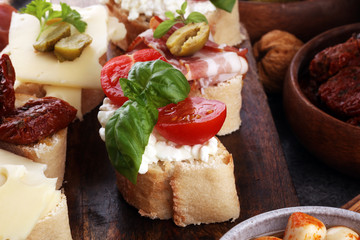 Italian antipasti wine snacks set. Cheese variety, Mediterranean olives, pickles, Prosciutto di Parma, tomatoes, artichokes and wine in glasses