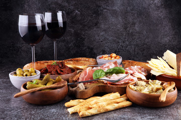 Italian antipasti wine snacks set. Cheese variety, Mediterranean olives, pickles, Prosciutto di Parma, tomatoes, artichokes and wine in glasses